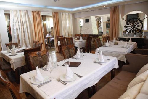 a dining room with tables and chairs with white table settings at Motel Restoran DURMITOR in Nikoljac