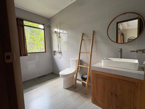 a bathroom with a sink and a toilet and a mirror at Raka Rai Bungalows in Ubud