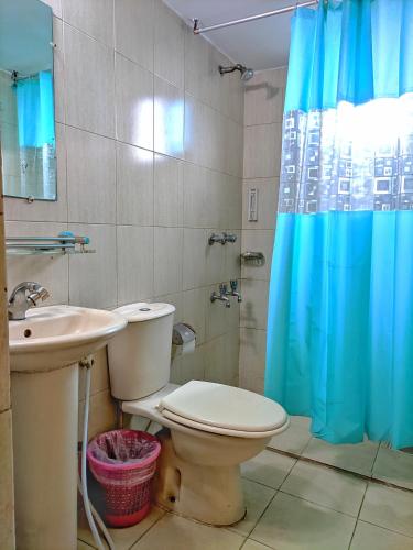a bathroom with a toilet and a sink and a blue shower curtain at Hotel Afford Inn in Dhaka