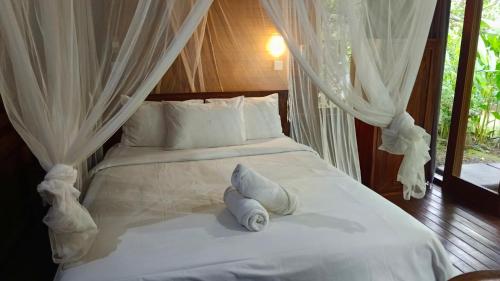 a bedroom with a bed with white sheets and pillows at Mulia Home Stay in Nusa Dua