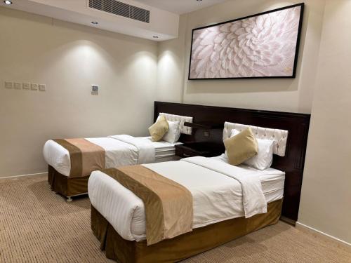 ein Hotelzimmer mit zwei Betten und einem Gemälde an der Wand in der Unterkunft راجان للشقق المخدومة in Ta'if