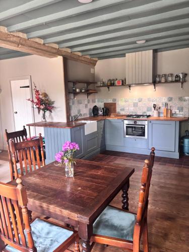 a kitchen with a wooden table with flowers on it at La Ramée - 2 bedroom - Wi-Fi - Garden - Parking in Saint-Siméon