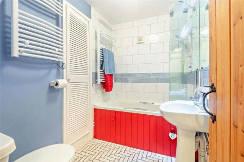 a bathroom with a tub and a sink and a toilet at Boatman's Cottage in Rhoscolyn