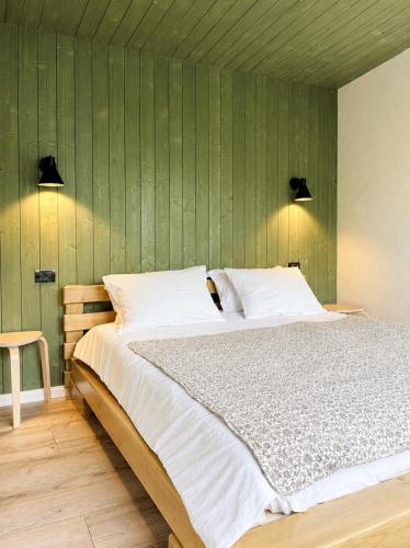 a bedroom with a large bed with a green wall at Tinutul Luanei Village in Bozioru