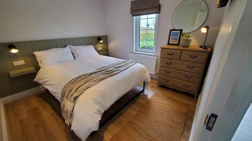 a bedroom with a bed and a dresser and a mirror at Sundaywell Cottage in Killyleagh