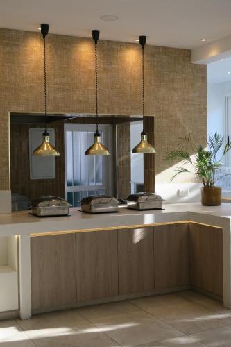 a bathroom with three lights hanging over a counter at Anonymous Beach Hotel (Adults 16+) in Ayia Napa