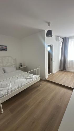 a bedroom with a white bed and a wooden floor at Vila DVG Tineret in Schitul