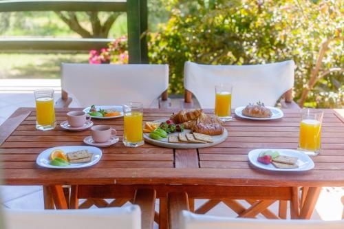 a wooden table with plates of food and glasses of orange juice at Emerald Cove in Kanali