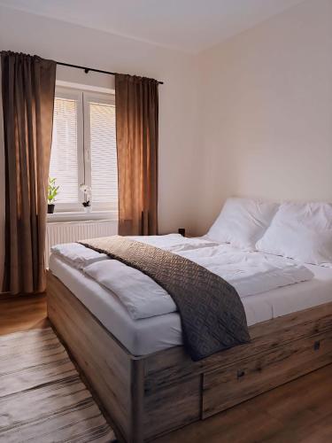 a bedroom with a large bed with white sheets and a window at Serenity Apartment in Mariánské Lázně