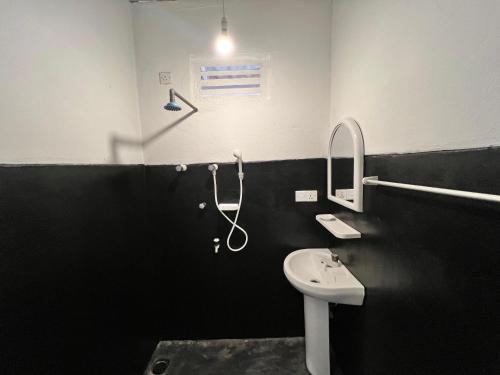 a black and white bathroom with a sink and a shower at Uluwatu Surf Hostel - Arugambay in Arugam Bay