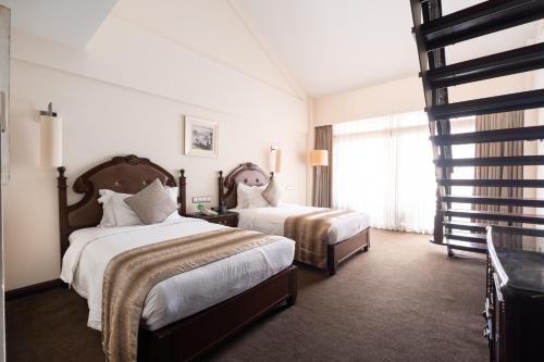 a hotel room with two beds and a mirror at Tang Palace Hotel in Accra