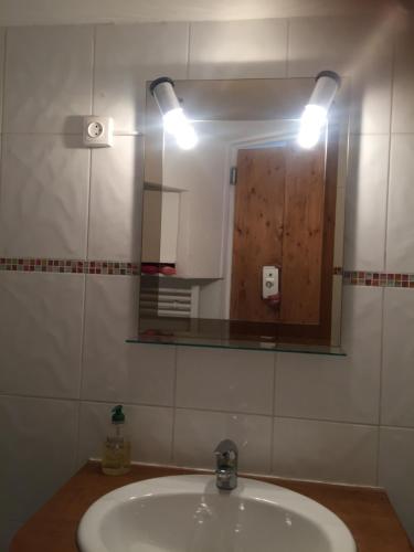 a bathroom with a sink with a mirror and a light at Chez Nahiko STUDIO Paris Massy Palaiseau in Palaiseau
