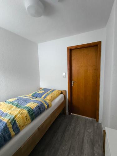 a small bedroom with a bed and a wooden door at FeWo Antweiler Oberdorf in Mechernich