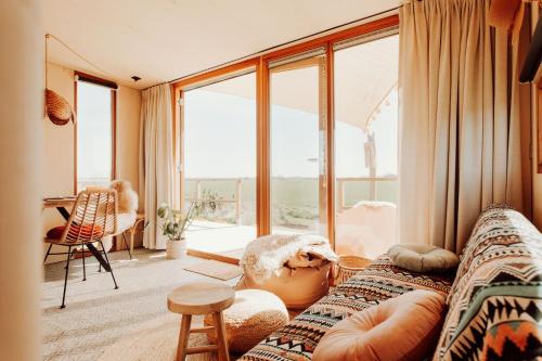 a living room with a couch and a large window at Tiny Cabana in Scharendijke