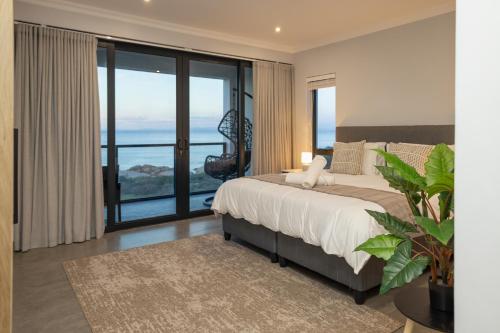 a bedroom with a bed and a large window at Taluga Beach Villa in St. Helena Bay