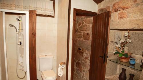 ein Badezimmer mit Toilette und einer Steinwand in der Unterkunft Casa do Sear - Turismo Rural & Spa Exterior in Sanxenxo