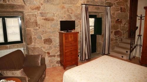 ein Wohnzimmer mit einer Couch und einem Fernseher auf einer Kommode in der Unterkunft Casa do Sear - Turismo Rural & Spa Exterior in Sanxenxo