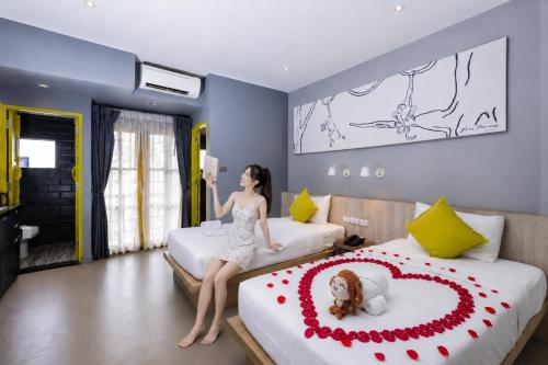 a woman in a dress sitting on two beds with a dog on it at Ploen Chaweng by Tolani in Chaweng