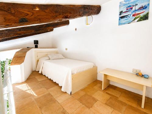 a white bedroom with a bed and a table at Casa al mare Porto Sole in Baja Sardinia