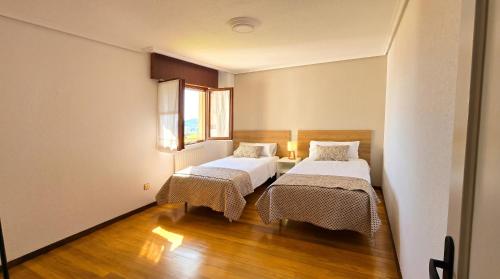 two beds in a small room with wooden floors at Las Vistas in Suances
