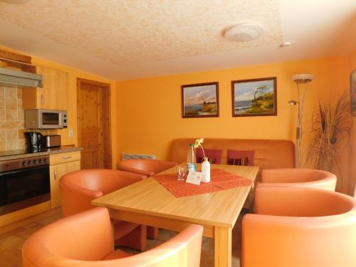 a kitchen with a wooden table and orange chairs at Sterntaucher Bungalow App 5 in Ahrenshoop