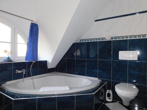 a blue tiled bathroom with a tub and a toilet at Haus Tina in Ahrenshoop