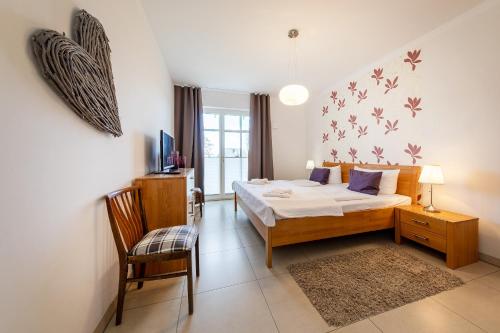 a bedroom with a bed and a chair and a television at Suite Meeresrauschen in Ahrenshoop