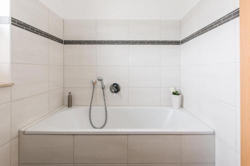 a bath tub in a bathroom with white tiles at Abendrot in Ahrenshoop