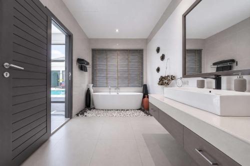 a bathroom with a tub and two sinks and a mirror at Exclusive Tropical Living! Elegant 4BR Villa Destiny with Salt Pool in Rawai Beach