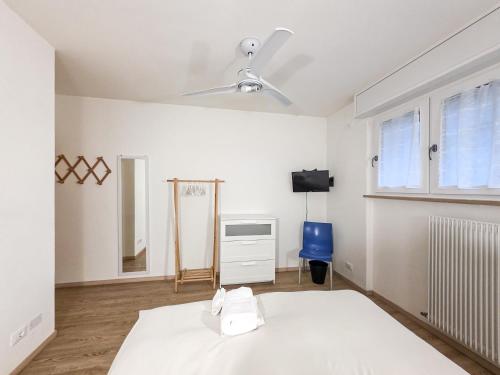 a white bedroom with a bed and a blue chair at B&B Color Rovereto in Rovereto