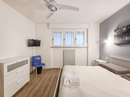 a white bedroom with a bed and a blue chair at B&B Color Rovereto in Rovereto