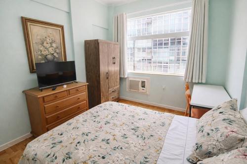 a bedroom with a bed and a television and a window at Apto Central com Wi-Fi Rápido e Workspace in Niterói