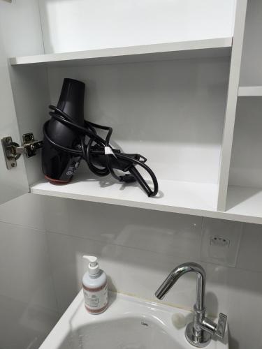 a sink in a bathroom with a black bag on a shelf at Apto Central com Wi-Fi Rápido e Workspace in Niterói