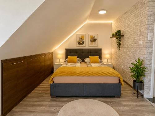 a bedroom with a large bed and a brick wall at Iva Penthouse in Novi Sad