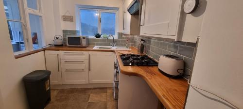 a kitchen with white cabinets and a counter top at Sage Cottage Ventnor in Ventnor