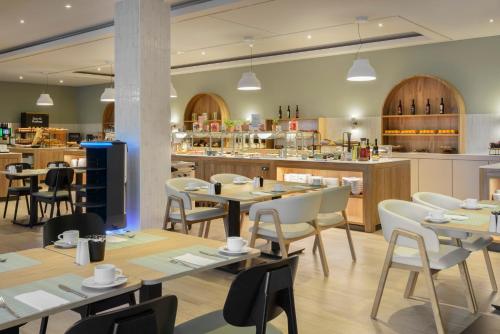 a restaurant with tables and chairs and a kitchen at Barceló Dresden Newa in Dresden
