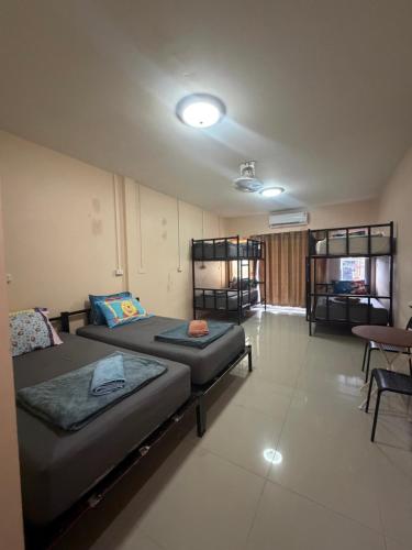 a room with two beds and a table and chairs at Khaosok city hostel in Khao Sok National Park