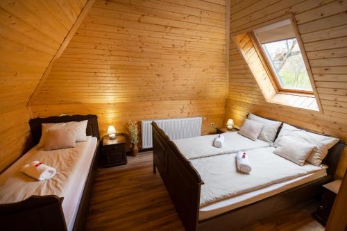 two beds in a room with wooden walls at Székelyföld,Siklódi Kő Vendégház Szénatároló in Şiclod
