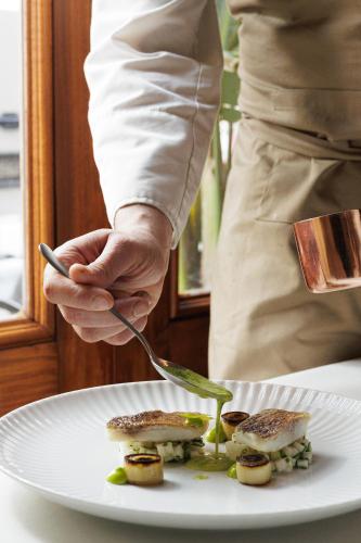 a chef is holding a fork and a plate of food at Athens 1890 Hotel & Spa in Athens