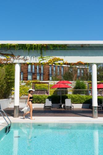 a woman walking next to a swimming pool at MOVE Hotels Venezia Nord in Mogliano Veneto