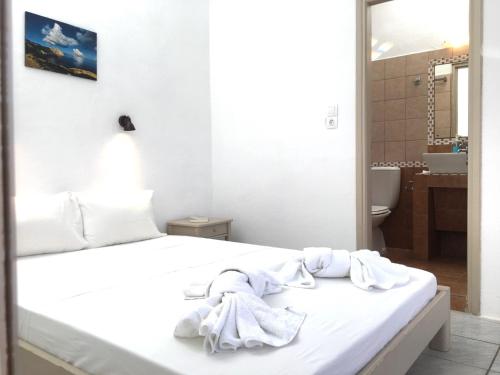 ein Schlafzimmer mit einem weißen Bett, auf dem Handtücher liegen in der Unterkunft Pavlosx2 in Folegandros Chora