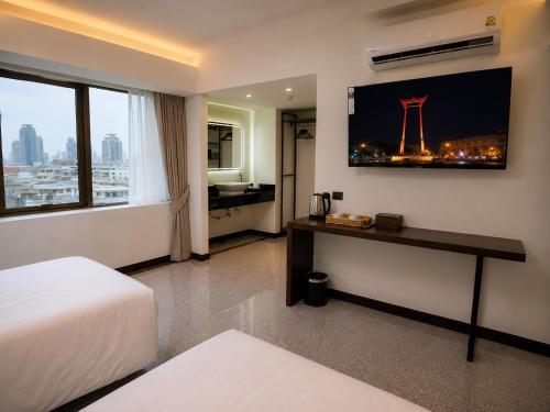 a hotel room with a bed and a desk and a window at The Wang Yaowarat Hotel in Bangkok