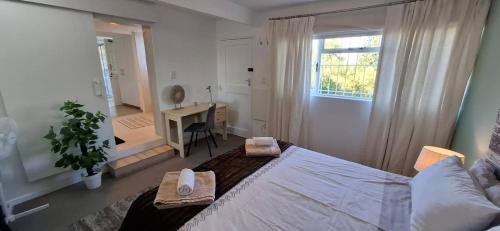 a bedroom with a bed and a desk and a window at Agape Apartments in Somerset West