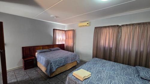 a hotel room with two beds and a bedskirtspectspectssenalsenalsenalsenal at Beginners Cove Lodge in Nelspruit