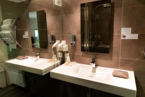a bathroom with two sinks and a mirror at Les Trois Soleils in Saint-Céré