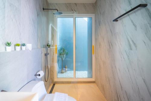 a bathroom with a toilet and a glass window at Luma & Malta PoolVilla Cha-am in Sathani Nong Ta Phot