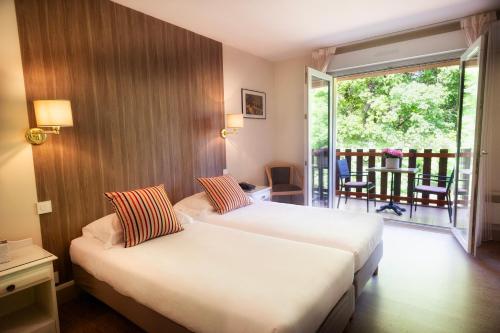 a hotel room with two beds and a balcony at Les Trois Soleils in Saint-Céré