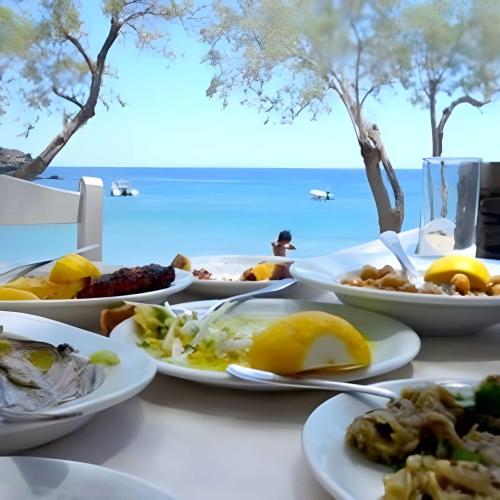 a table with plates of food on a table near the beach at Camping Dias in Gythio