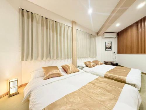two beds in a bedroom with white and brown at クリスタルSky tree Hotel in Tokyo