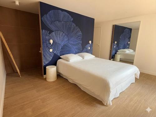 a bedroom with a large white bed and a blue wall at Appartement avec jacuzzi et vue sur Pyramide in Vienne